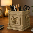 CONQR military ammo box pen stand in desert sand on a wooden desk under lamp light